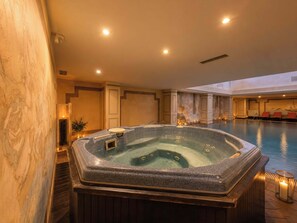 A hot tub in a hotel lobby with a pool and seating area.