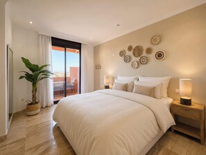 Ein geräumiges Schlafzimmer mit einem großen Bett, einem Balkon mit Aussicht und dekorativen Wandbildern.