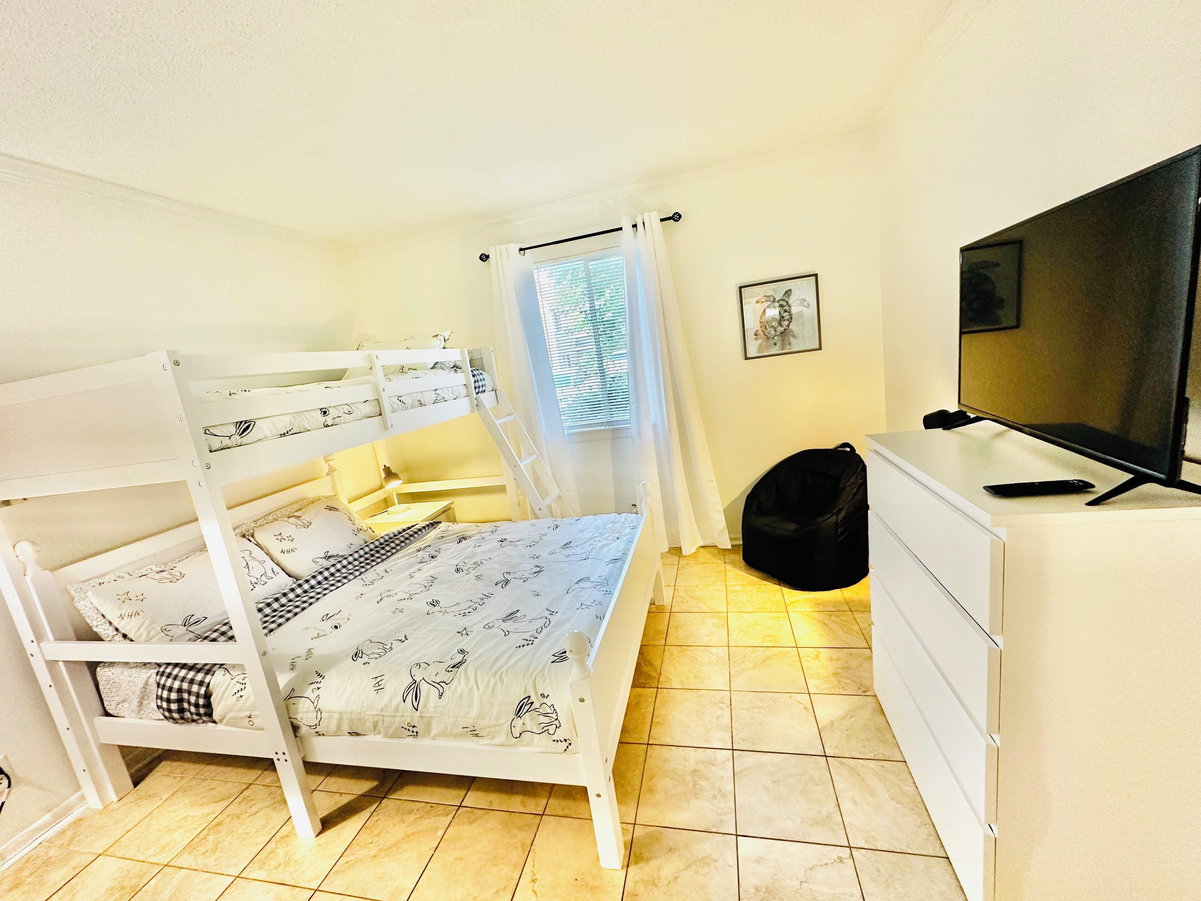 A bunk bed room with a television and a desk.