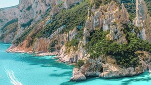 Eine Küstenlandschaft mit einem markanten Felsen und klarem türkisblauem Wasser.