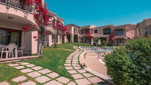 A hotel courtyard with a swimming pool, stone pathways, and outdoor seating.
