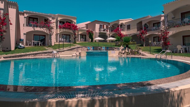 A swimming pool surrounded by a courtyard with multiple buildings, each with balconies and outdoor seating.