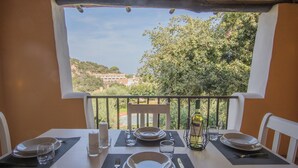 A dining table set for two with a view of a balcony and trees.