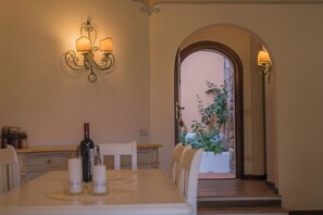 Un coin repas avec une table dressée pour quatre personnes, une bouteille de vin, des bougies et une plante en pot.