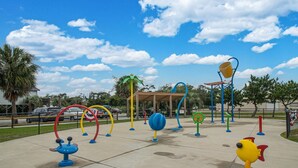A playground with various colorful play structures, including swings and climbing equipment, under a clear blue sky. - Charming Home! Just minutes From the Beach, Near Shopping, Dog Friendly (Oak Island)