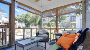 A covered patio with wicker furniture, a glass table, and a view of the backyard. - Charming Home! Just minutes From the Beach, Near Shopping, Dog Friendly (Oak Island)