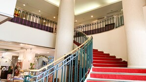 A multi-level interior with a staircase, columns, and a railing.