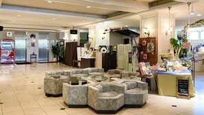 A spacious lobby with a seating area featuring a glass-top coffee table surrounded by sofas.