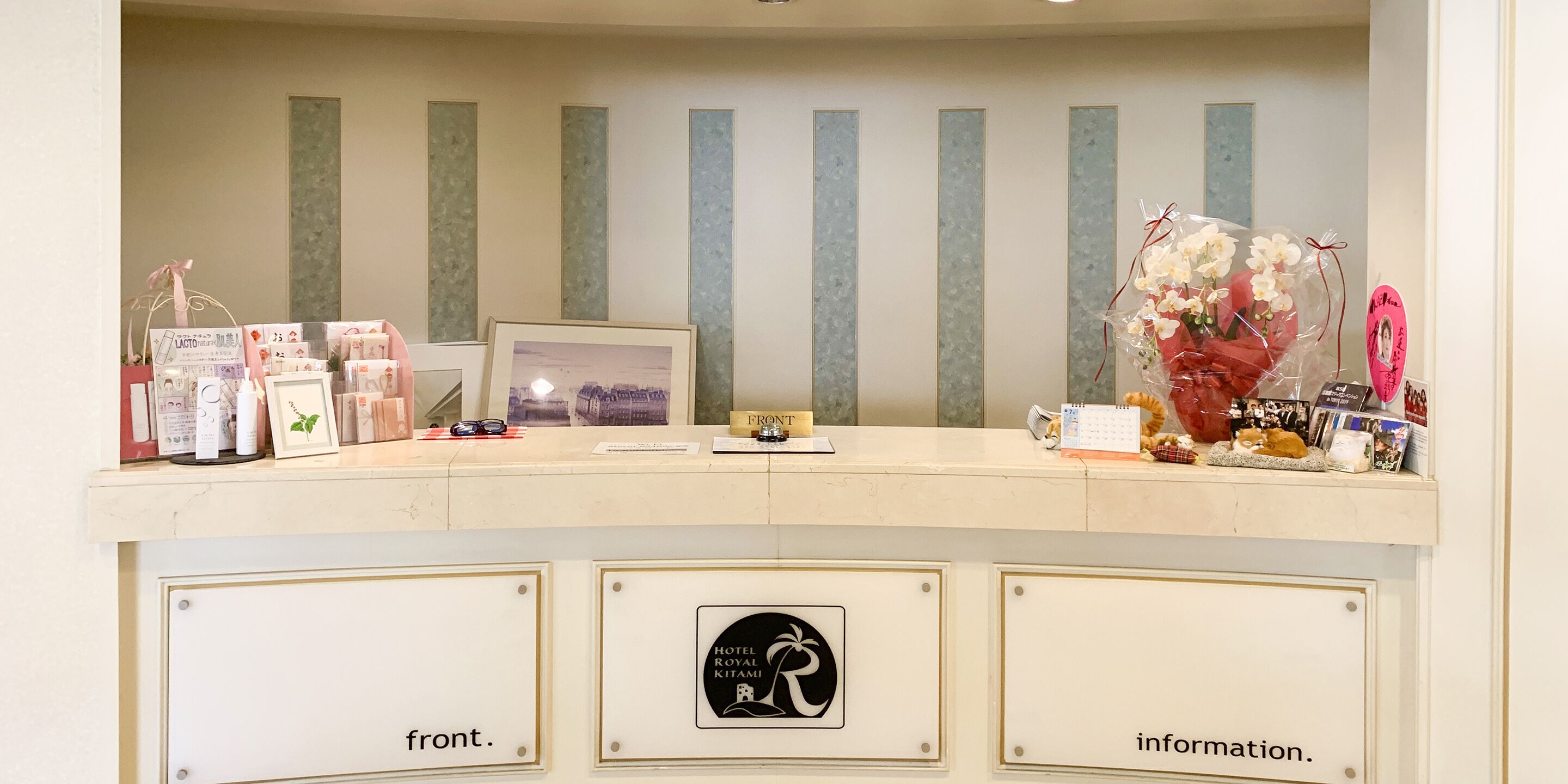 Balcão de recepção de hotel com uma moldura, um calendário e vários objetos sobre o balcão.
