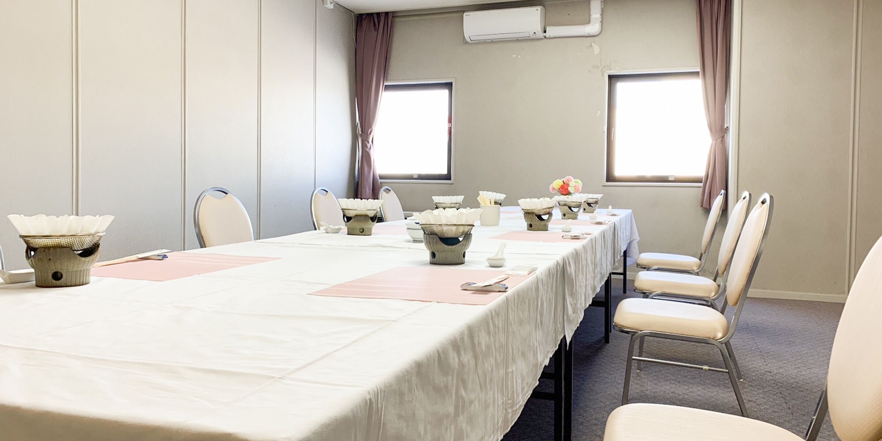 Une salle de conférence avec une longue table, des chaises et une fenêtre.