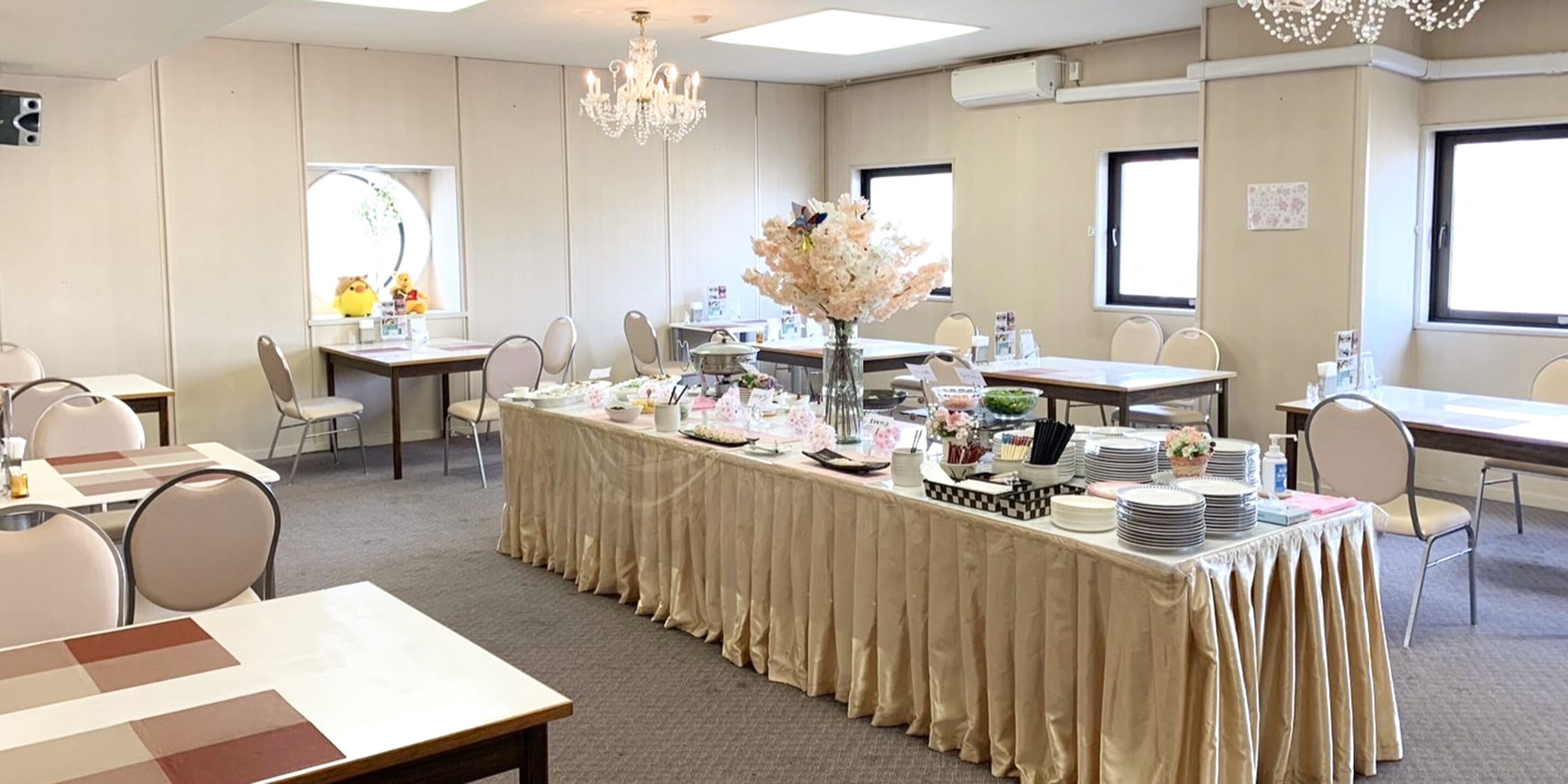 Un salón de conferencias con una larga mesa cubierta con un mantel color beige, rodeada de sillas.
