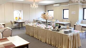 Un salón de conferencias con una larga mesa cubierta con un mantel color beige, rodeada de sillas.