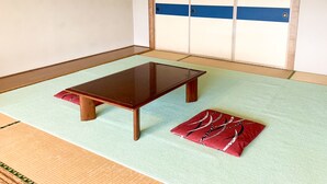 A tatami mat room with a wooden table and a red cushion.