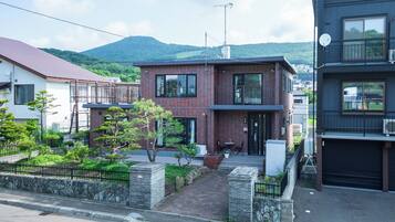 A modern two-story house with a brick facade, a small front porch, and a mountain in the background.