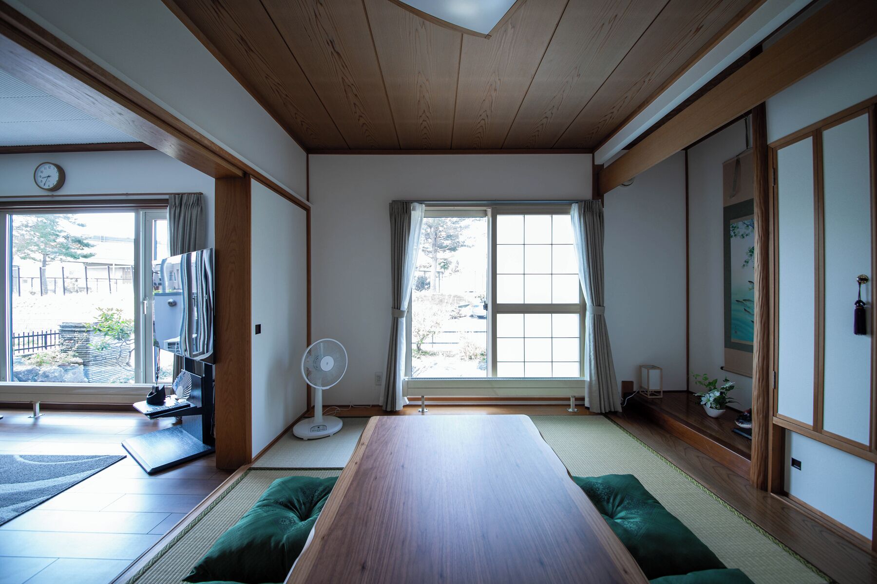 A traditional Japanese room with tatami flooring, a wooden table, sliding doors, and a view of the outside.