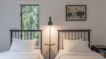 Una habitación con dos camas, una mesita de noche, una lámpara de pie y un cuadro en la pared.