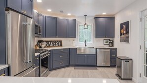 Une cuisine moderne avec des meubles de couleur sombre, des appareils électroménagers en acier inoxydable et un îlot central.