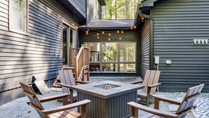 Une terrasse avec des fauteuils Adirondack, un foyer et une guirlande lumineuse.