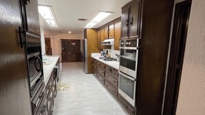 Une cuisine dotée d’un îlot central, d’appareils électroménagers intégrés et d’un revêtement de sol en carrelage.