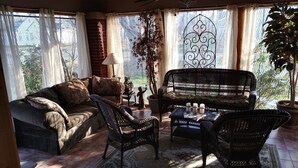 A sunlit room with a sofa, two armchairs, a coffee table, and a potted plant.