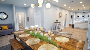 Un comedor moderno con una mesa de madera, individuales tejidos, velas y una lámpara colgante.