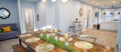 Un comedor moderno con una mesa de madera, individuales tejidos, velas y una lámpara colgante.