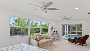 Une pièce spacieuse avec un grand lit, un canapé, un fauteuil et une vue sur une piscine.