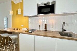 A modern kitchen with a wooden countertop, white cabinets, a stainless steel sink, and pendant lights.