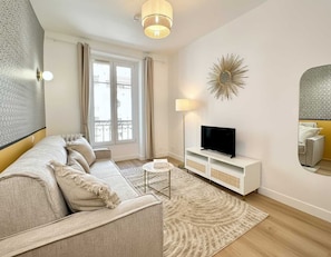 A modern living room with a sofa, TV, and decorative wall art.
