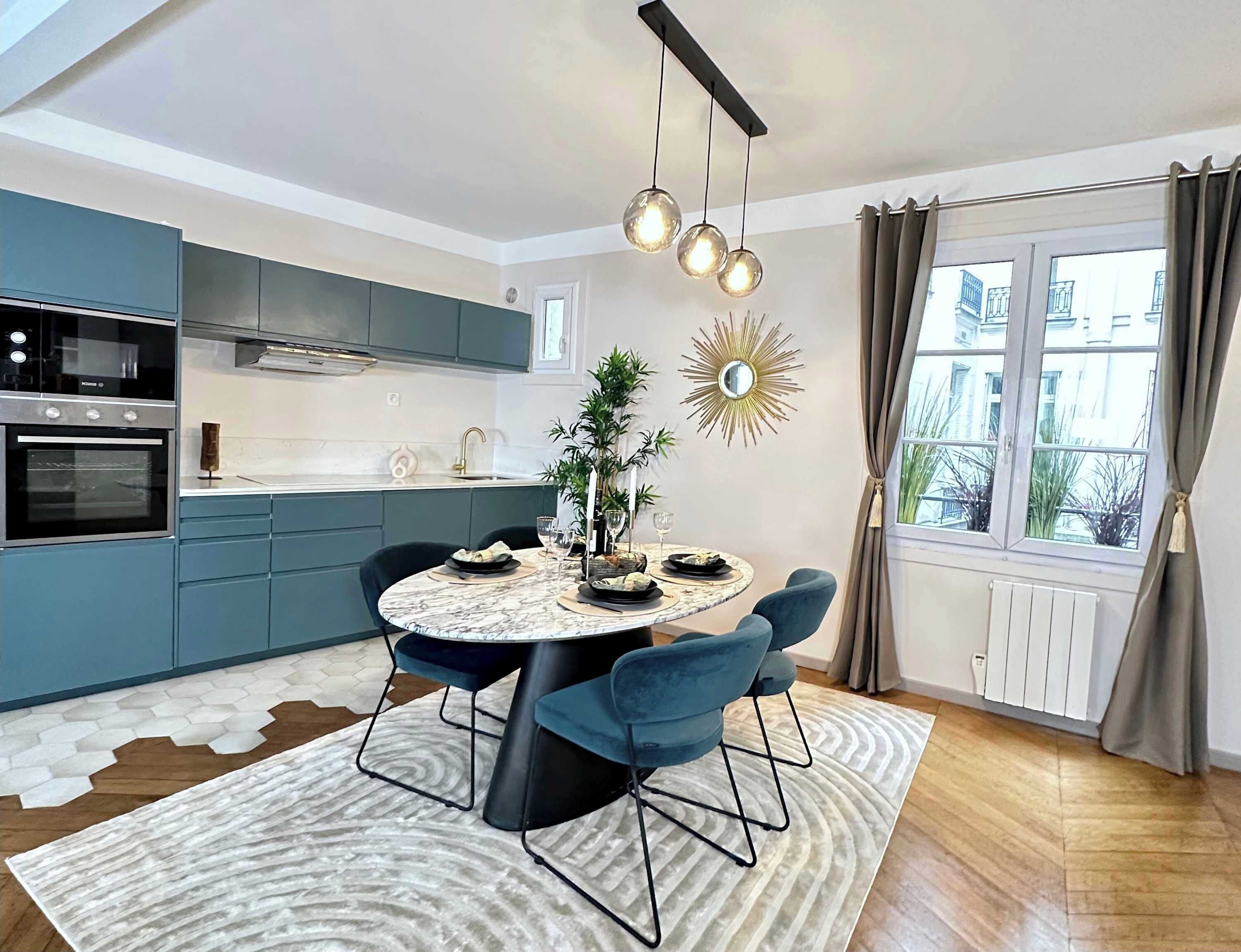 Een moderne keuken met een inbouwoven, een eettafel met stoelen, een decoratieve spiegel en uitzicht buiten door een raam.
