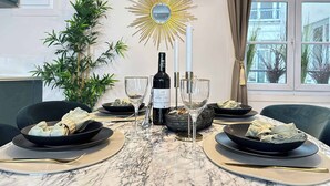 A dining table set with plates, glasses, a bottle, and a decorative mirror.