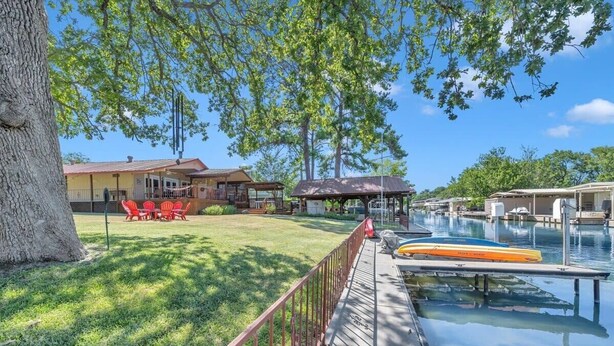 A pool area with a wooden deck, a covered seating area, and a building in the background.