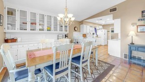 A spacious kitchen with white cabinetry, a wooden dining table, and blue chairs.