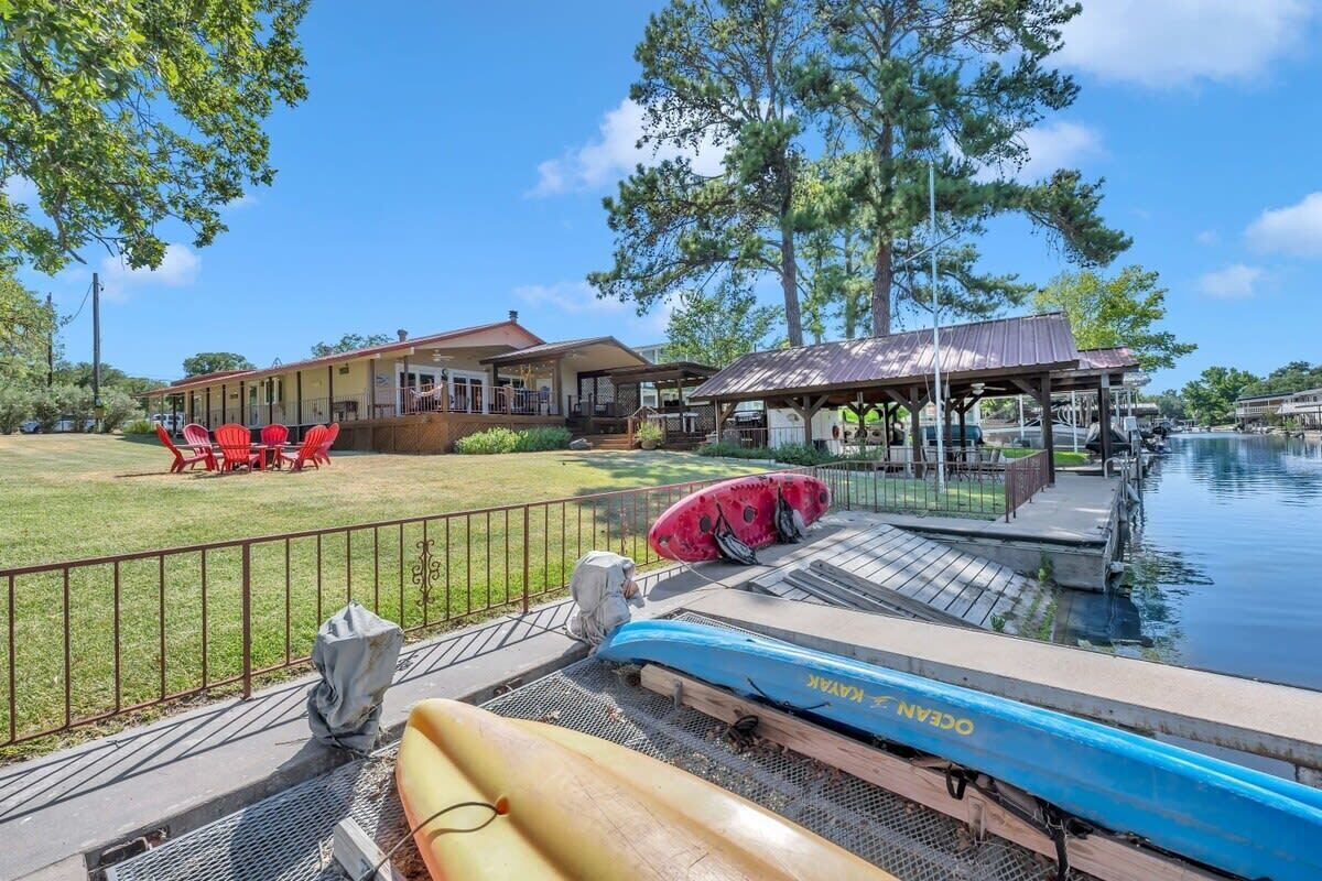 A lakeside property with a dock, kayaks, and a building with outdoor seating.