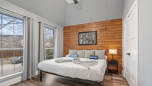 Une chambre avec un grand lit, un mur décoratif en bois et une vue sur l’extérieur.