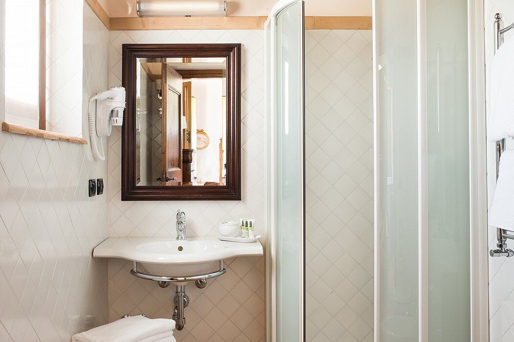 Een badkamer met een wit wastafelmeubel, een spiegel en een douchecabine met glazen wanden.