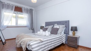 Ein ordentlich eingerichtetes Schlafzimmer mit einem Bett, Nachttischen und einem Fenster mit Vorhängen.