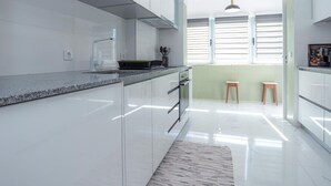 Eine moderne Küche mit weißen Schränken, einer Arbeitsplatte aus Granit und einem kleinen Hocker.