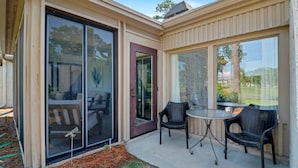 A covered patio with a sliding glass door, a small table, and two chairs.