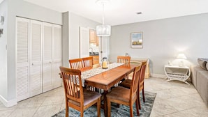 A dining area with a wooden table and chairs, a chandelier, and a framed picture on the wall.