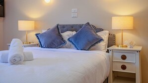 A neatly made bed with a white duvet, two bedside lamps, and a nightstand with a lamp and a decorative item.