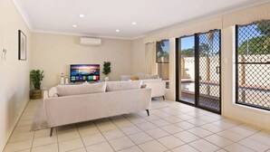 A spacious living room with a large flat-screen TV, a sofa, and a dining area.