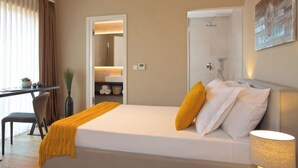 Moderni hotellihuone, jossa on suuri sänky, työpöytä ja suihkutila.