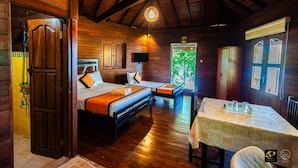 A wooden cabin with two beds, a dining table, and a view of greenery outside. - The Thotupola Habaraduwa (Koggala)