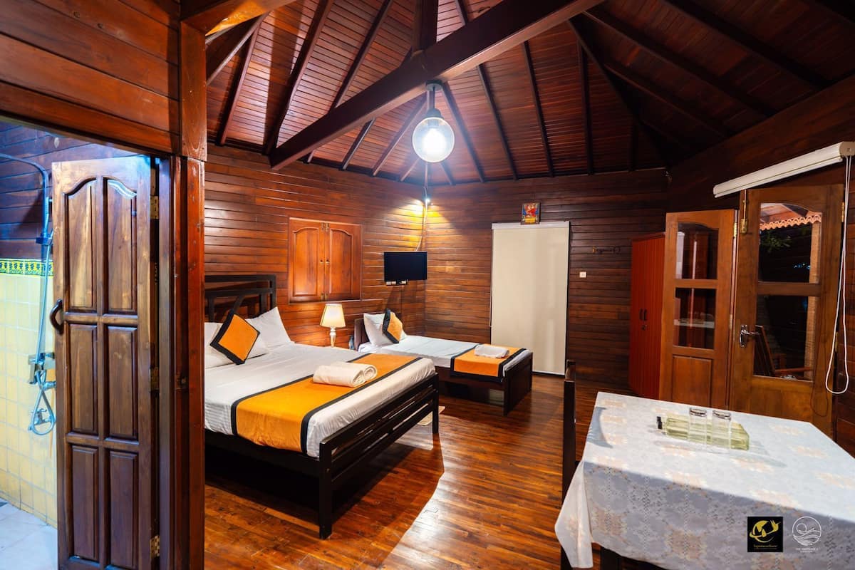 A wooden cabin-style room with two beds, a table, and a TV.
