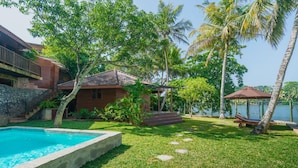 A pool surrounded by a grassy lawn, a wooden house, and a gazebo. - The Thotupola Habaraduwa (Koggala)