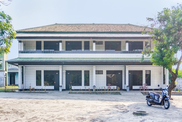 A two-story building with a tiled roof and a balcony.