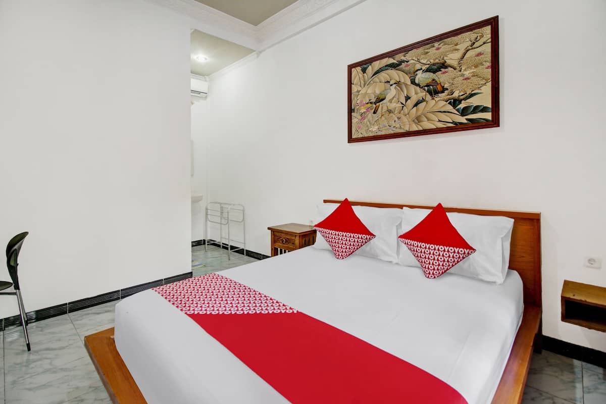 A hotel room with a large bed, a wooden headboard, and a painting on the wall.
