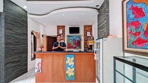 A reception area with a wooden counter, a TV mounted on the wall, and a colorful fish painting above the counter.