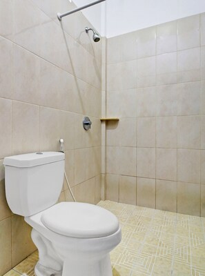 A bathroom with a toilet, a shower, and tiled walls.